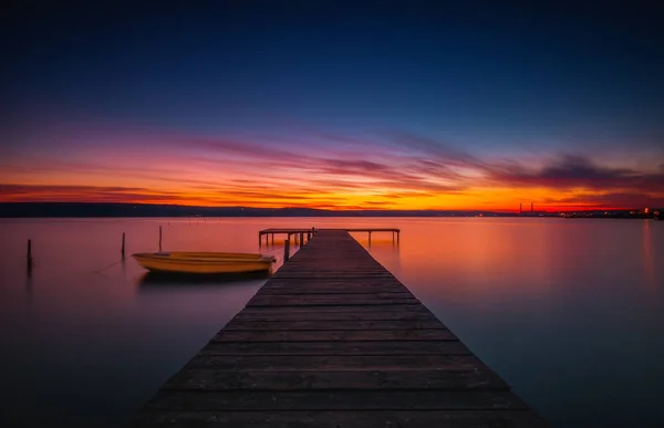 Fából készült dokk és csónak a tó, naplemente szemcsésedik — Stock Fotó