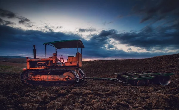 Alter rostiger Traktor auf einem Feld bei Sonnenuntergang. — Stockfoto