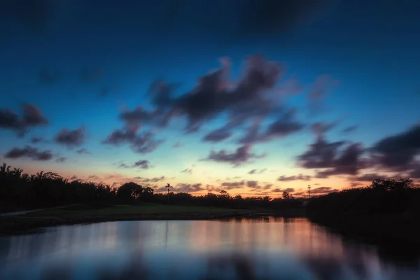Закат над озером рядом с полем для гольфа в небольшом городке — стоковое фото