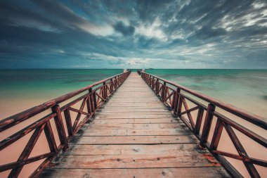 Wooden jetty reaching into the turquoise Caribbean sea clipart