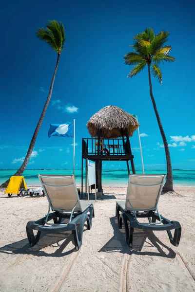 Palmeiras, cadeiras de sol e estação de salva-vidas na praia tropical — Fotografia de Stock