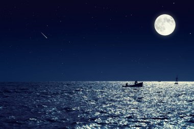 Gece sakin deniz suyundaki küçük balıkçı teknesi doğal görünümünü ve