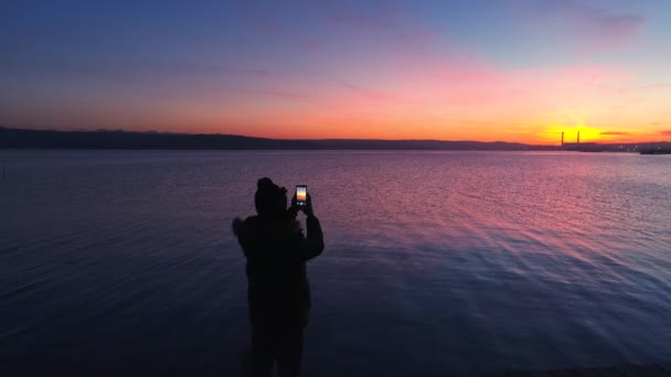 小さなドックと美しい朝焼けの湖でボートを空中ドローン フライト 夕日と写真を作る楽しみを男します — ストック動画