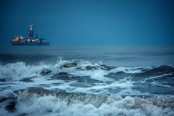 Серфер ловит огромные волны в глубоководных водах после захода солнца. Парусник . — стоковое фото