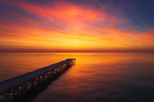 Luftaufnahme über die alte kaputte Brücke im Meer, Sonnenaufgangsaufnahme. — Stockfoto