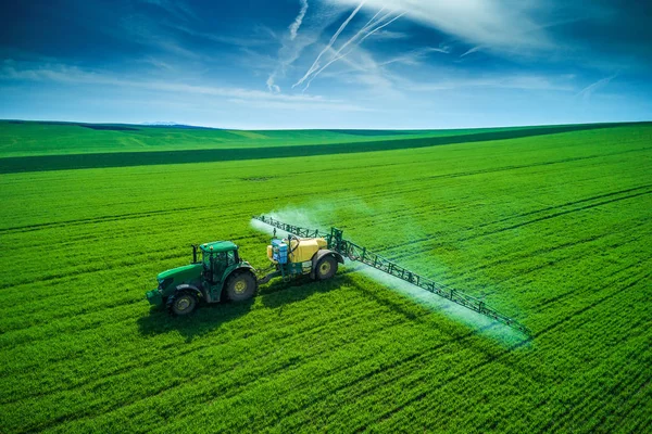 Vista aérea del tractor agrícola arando y pulverizando en el campo — Foto de Stock