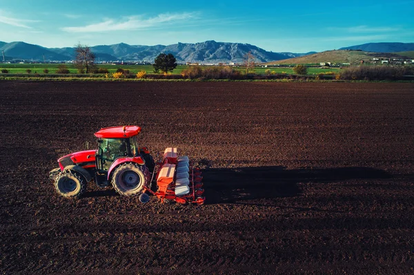 Agricultor com culturas de sementeira de tractores no campo — Fotografia de Stock