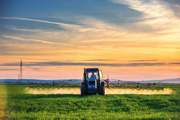 Ackerschlepper pflügt und sprüht auf Feld — Stockfoto