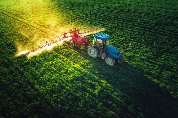 Vista aérea del tractor agrícola arando y pulverizando en el campo — Foto de Stock