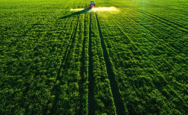 Aerial view of farming tractor plowing and spraying on field — Stock Photo, Image