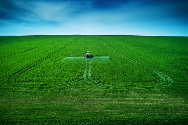 Vista aérea del tractor agrícola arando y pulverizando en el campo —  Fotos de Stock