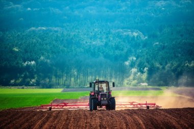 Traktördeki çiftçi tohum ekiciyle toprağı hazırlıyor.