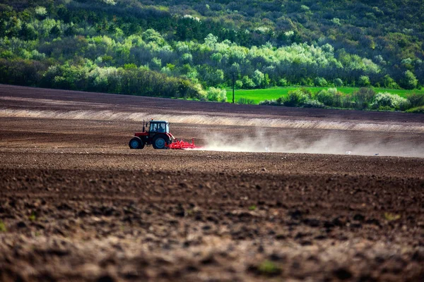 Farmer with tractor seeding crops at field — Stock Photo, Image