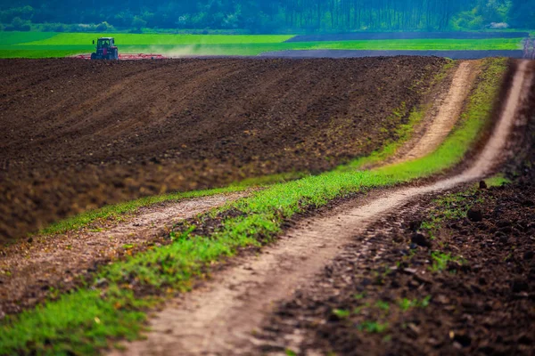 Agricultor com culturas de sementeira de tractores no campo — Fotografia de Stock