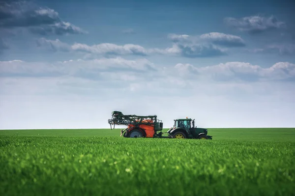 Zemědělský traktor orání a postřik na poli — Stock fotografie