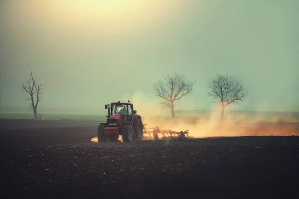 Farmář v traktoru připravuje půdu s kultivátorem seťového lůžka — Stock fotografie