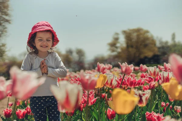 Kleines schönes Mädchen im Blumenpark — Stockfoto