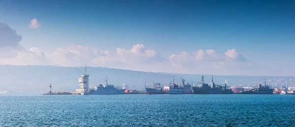 Porto marítimo Varna, Bulgária e bela paisagem matinal. Navios de carga, guindastes industriais e torre de navegação . — Fotografia de Stock