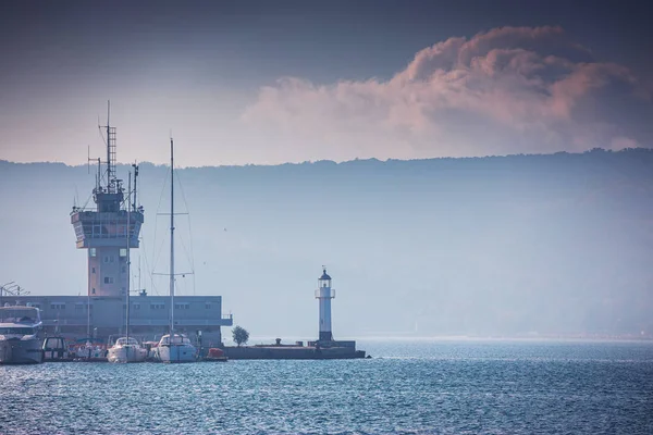 Морской порт Варна, Болгария и красивый утренний пейзаж. Маяк, рыбацкие лодки, яхты и навигационная башня — стоковое фото