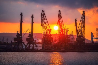 Bulgaristan 'ın Varna kentinde deniz limanı ve sanayi vinçleri üzerinde gün batımı