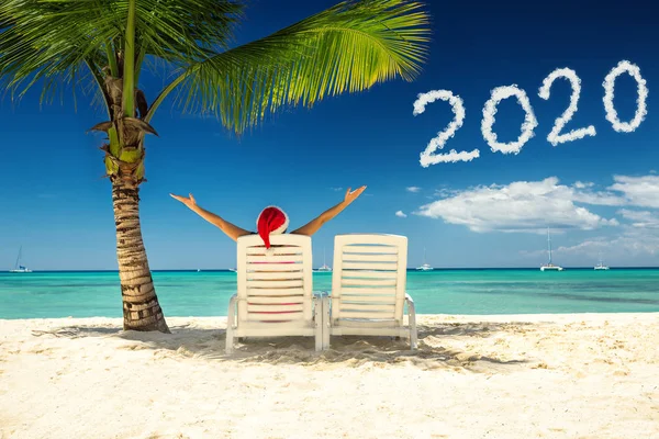 Mujer con sombrero de santa relajándose en la playa tropical. Feliz año nuevo 2020 — Foto de Stock