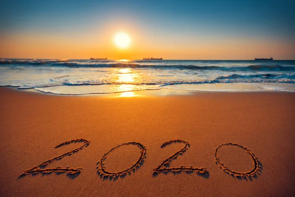 Frohes neues Jahr 2020 Konzept, Schriftzug am Strand. Sonnenaufgang am Meer — Stockfoto