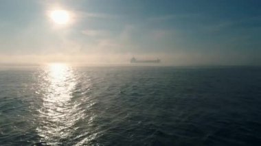 Kargo konteynır gemisinin hava görüntüsü, deniz sisi içinde yelkenler, teslimat konteynırları için çalışan vinç gemisi.
