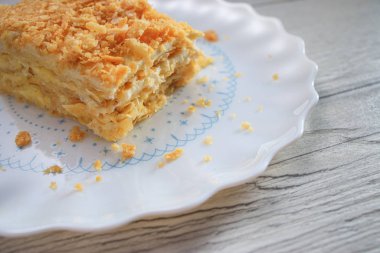 Beyaz izole bir tabak üzerinde vanilyalı süt kreması ile Napolyon kek