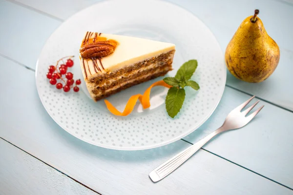 Pedaço de bolo de cenouras com creme de leite, cenouras e nozes isoladas — Fotografia de Stock