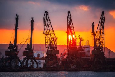 Bulgaristan 'ın Varna kentinde deniz limanı ve sanayi vinçleri üzerinde gün batımı