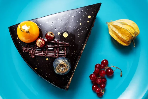 Chocoladetaart met decoratie en fruit op blauwe achtergrond — Stockfoto