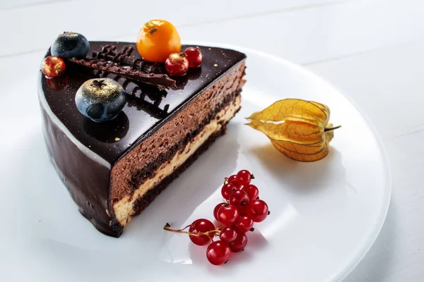Torta al cioccolato con decorazione e frutta su sfondo bianco in legno — Foto Stock