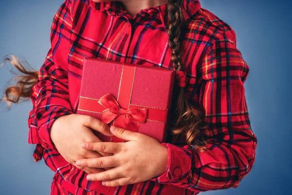 Little girl holds gift box with ribbon in hands on blue background — 스톡 사진