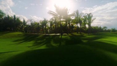 Lüks tropikal tatil köyündeki golf sahasında. Spor sahalarında, bahçelerde ve palmiyelerde gün batımı.