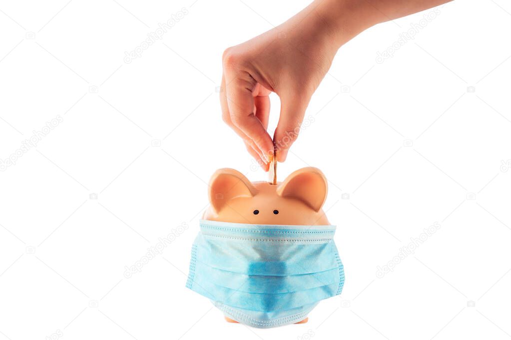 Hand putting money coin into piggy bank with mask for saving money wealth and financial concept