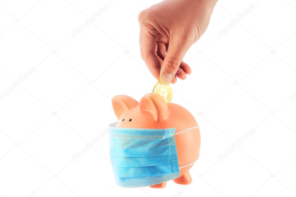 Hand putting golden bitcoin into piggy bank with mask for saving money wealth and financial concep