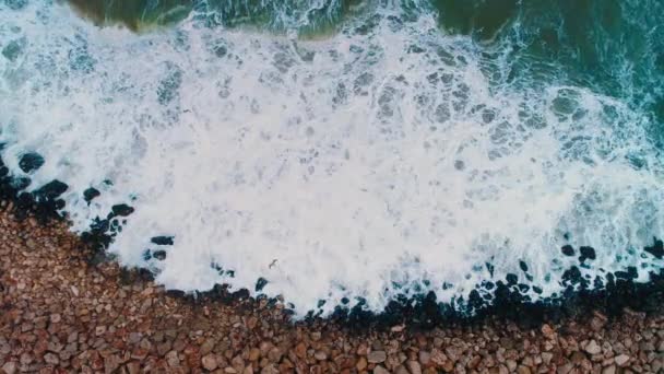 ビーチで岩を打つ海の波の空中トップビュー — ストック動画