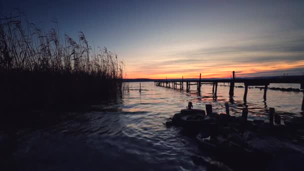 日没時に水の反射と海の湖の上の木製の桟橋 — ストック動画