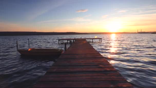 夕暮れ時に水面に映る湖の上のボートと木製の桟橋 — ストック動画