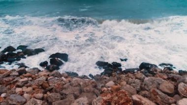 Dalgalar kıyı şeridinde kayalara çarpıyor.