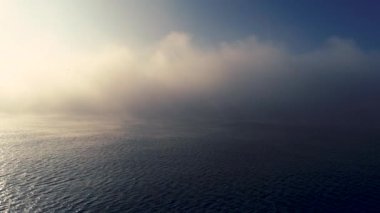 Okyanus dalgaları üzerinde sisli bir sabah. Güneş doğar ve dalgalanır su, hava manzarası