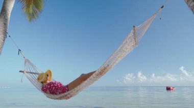 Tropikal ada sahilinde bir hamakta dinlenen kız. Punta Cana yaz tatili, Dominik Cumhuriyeti