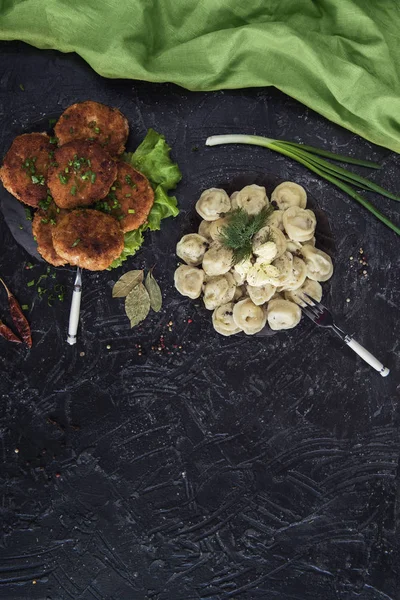 Chuletas fritas y pelmeni ruso sobre fondo negro — Foto de Stock