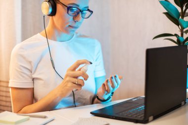Kadın telefonun yüzeyini dezenfekte ediyor.