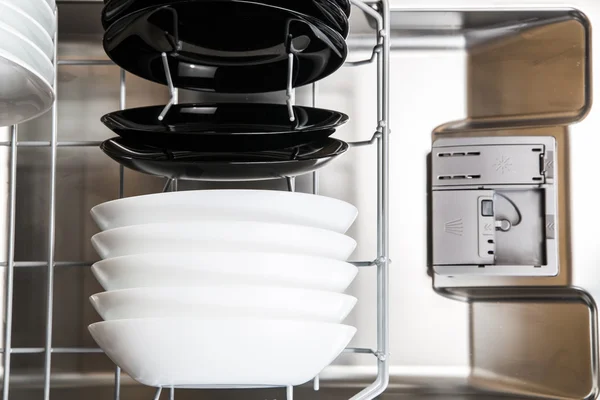 Weiße und schwarze Teller in der modernen Spülmaschine — Stockfoto