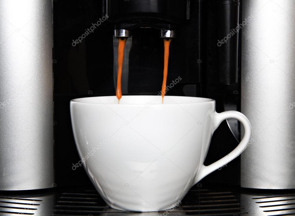 Espresso pouring from coffee machine into cup
