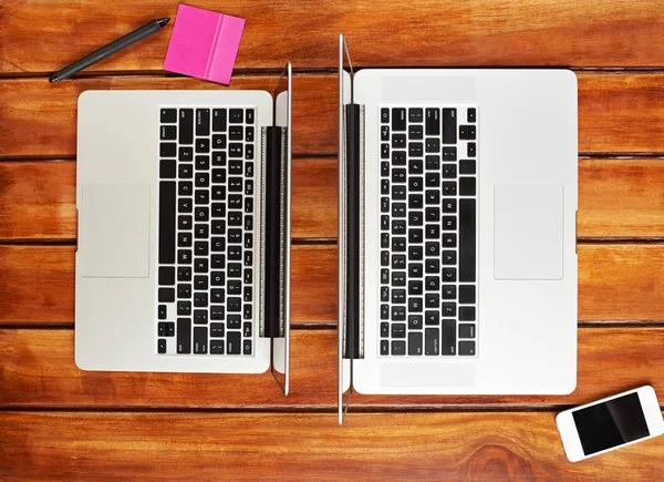 Dwa laptopy na drewnianym stole brązowy — Zdjęcie stockowe