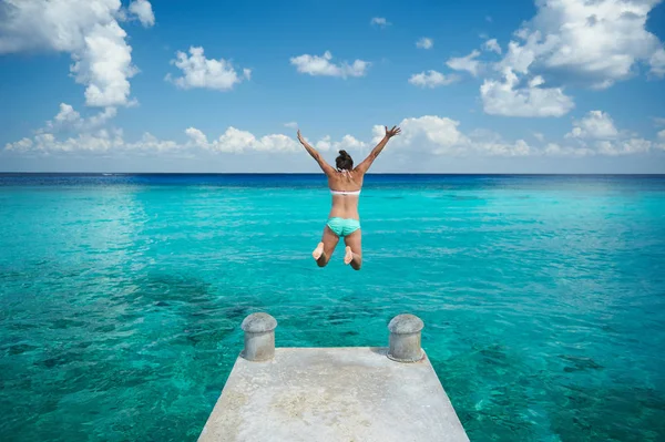 Een vrouw springt in blauw water — Stockfoto