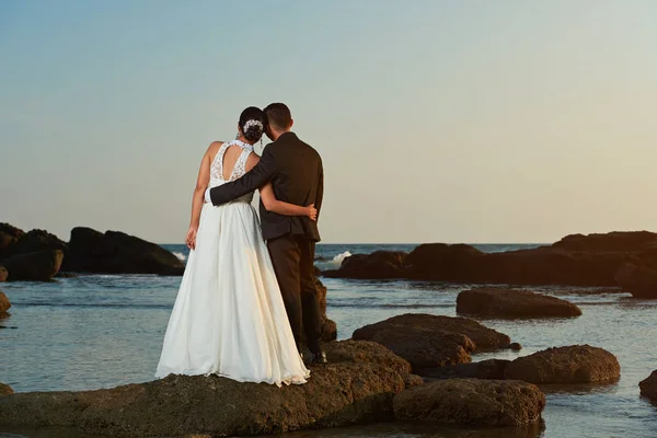 Manželský pár sledovat západ slunce na pláži u oceánu — Stock fotografie