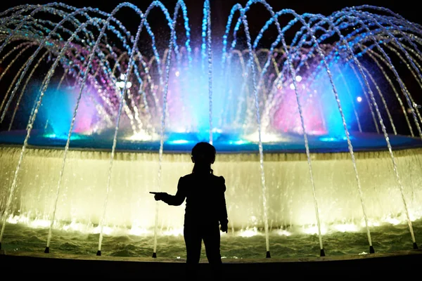 Małe dziecko grać z kolorowe fontanny — Zdjęcie stockowe